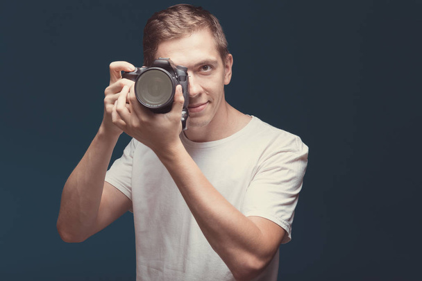 Smiling Man with camera isolated on dark background. Young man h - Photo, Image