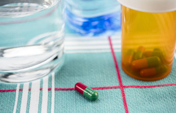 Medication during breakfast, capsules next to a glass of water, conceptual image, horizontal composition - Photo, Image