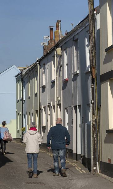 Appledore, North Devon, Angleterre, RU. Février 2019. Couple en bottes de marche marchant sur une rue très étroite de maisons en terrasses dans cette ville populaire du Devonshire en hiver
 - Photo, image
