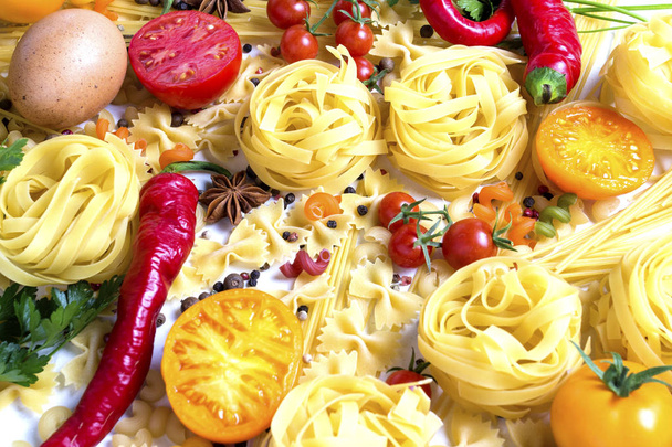 様々 なスパイス、赤唐辛子、鶏の卵、白地に黄色と赤のトマトのイタリアンのパスタ。イタリアンのパスタとソースの料理のコンセプト - 写真・画像