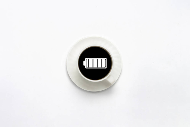 Taza blanca en un platillo, café negro, fondo blanco. Signo de batería. Piso tendido, vista superior
 - Foto, imagen