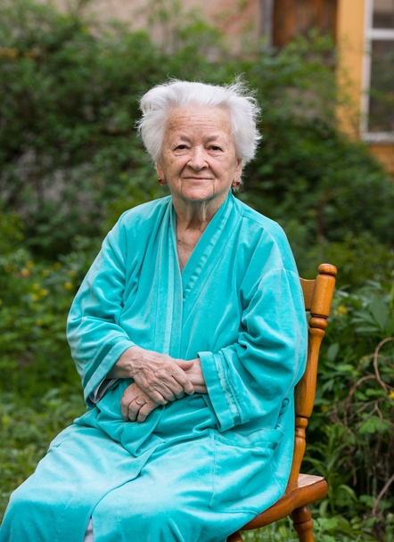 Smiling old womansitting on a chair - Photo, Image