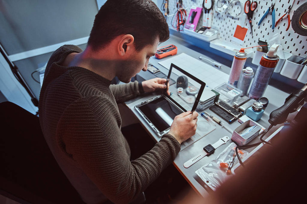 The technician repairs a broken tablet computer in a repair shop - Foto, imagen