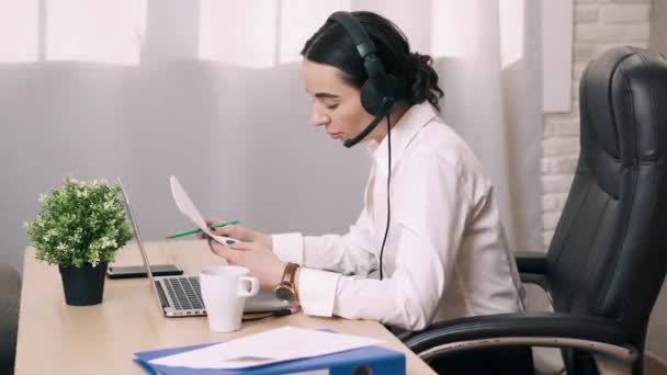 Trabajadora del centro de llamadas responde a llamada del cliente en la oficina - Metraje, vídeo