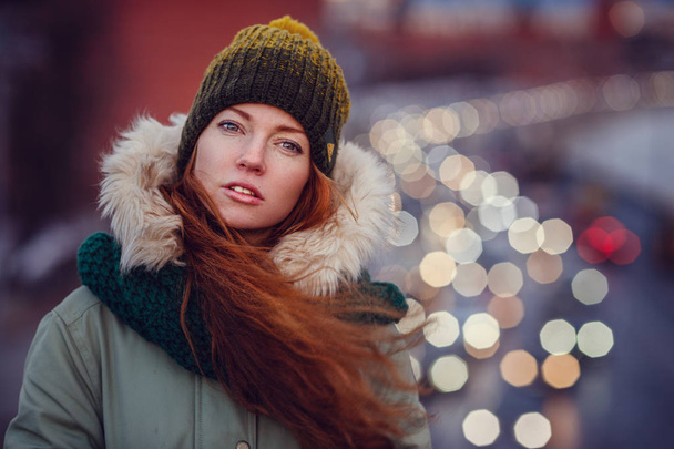 Szczęśliwa radosna dziewczyna w płaszczu spacerująca ulicą w chłodny zimowy wieczór o zachodzie słońca - Zdjęcie, obraz