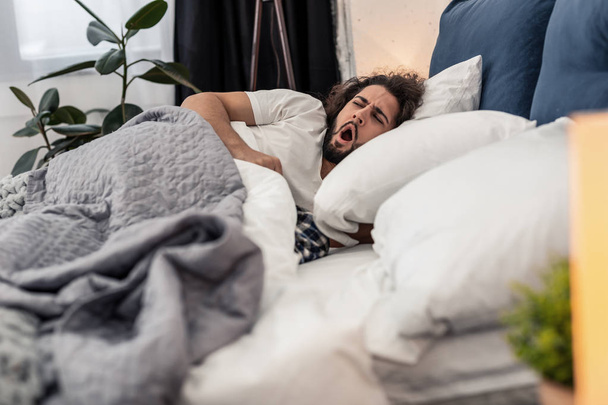 Sleepy young man yawning in the bed - Фото, зображення