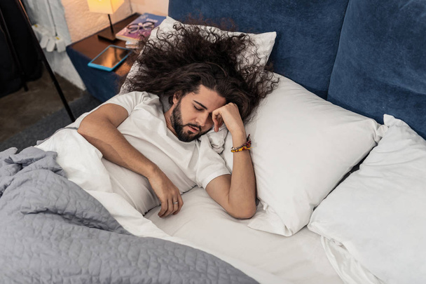 Charmant homme aux cheveux longs essayant de dormir
 - Photo, image