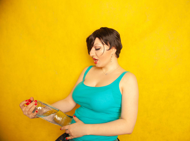 wesoła dziewczyna z krótkimi włosami z dużą butelkę wody na żółtym tle w Studio - Zdjęcie, obraz