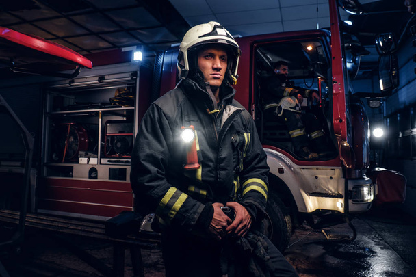 De brandweer kwam het gesprek op de nacht. Knappe brandweerman dragen van een beschermende uniform met een zaklamp opgenomen - Foto, afbeelding