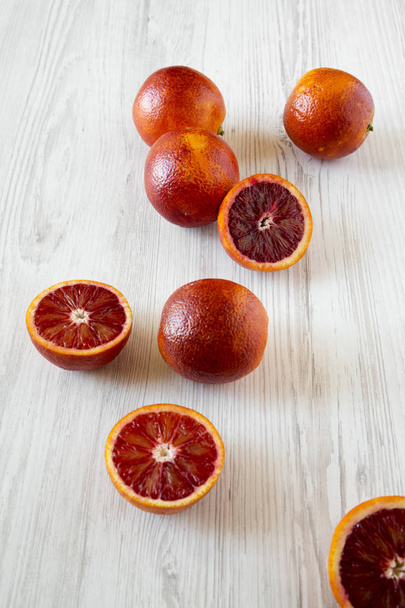 Całą i połowę Krwiste pomarańcze na białych drewnianych powierzchni, niskiej angl - Zdjęcie, obraz
