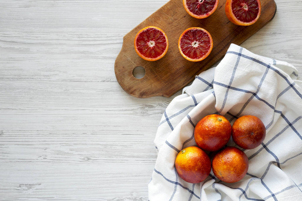 Whole and halved blood oranges on a white wooden background, top - Фото, зображення