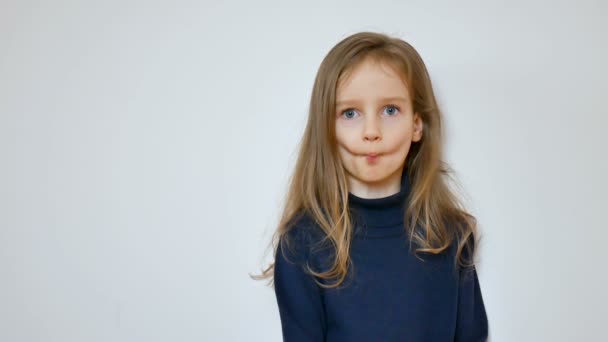 Крупним планом портрет милої дівчини з довгим світлим волоссям і великими блакитними очима гризти під час позування в студії
 - Кадри, відео