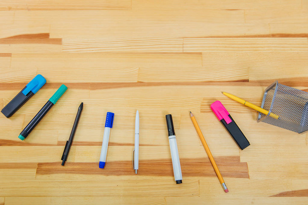 Офисный стол с аксессуарами: маркер синего и розового цветов, ручка, ручка, карандаш
. - Фото, изображение