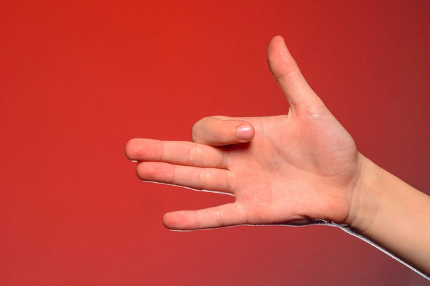 Emberi kéz, elszigetelt mutatja a kutya jel, a barátság, az állat és ember szimbolizáló piros alapon - Fotó, kép