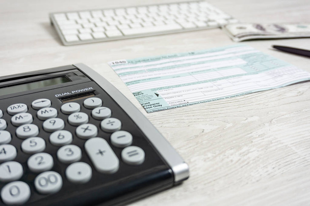 US tax form next to computer keyboard, calculator and tax form 1040. tax form us business income office hand fill concept - 写真・画像