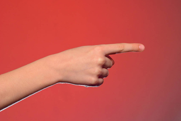Человеческая рука, показывающая указательный палец на объекте, изолированном на красном фоне
 - Фото, изображение