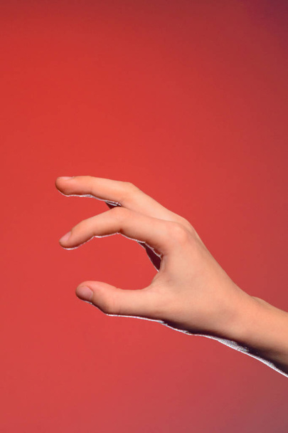 Ludzką ręką, składany razem wziąć trochę małe, na białym tle na czerwonym tle - Zdjęcie, obraz