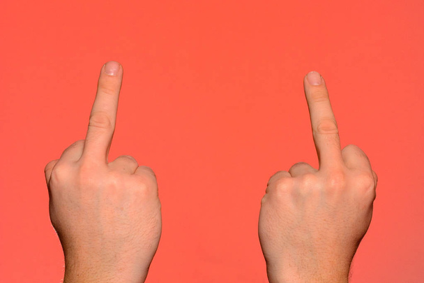 Menselijke hand tonen een obsceen gebaar met een middelvinger geïsoleerd op een rode achtergrond. - Foto, afbeelding