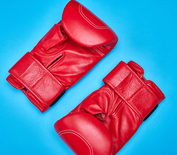пара червоних шкіряних боксерських рукавичок на синьому фоні
 - Фото, зображення