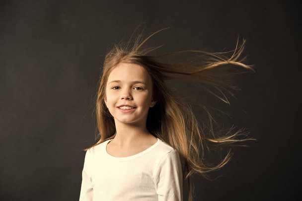 Natural beauty. Girl kid long hair flying in air, black background. Child with natural beautiful healthy hair. Quick tips for healthy hair. Growing hair recommendation. Extremely effective product - Photo, Image