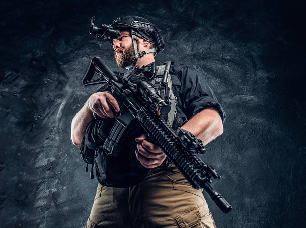 Vousatý speciálních sil voják nebo soukromých vojenských dodavatel drží útočná puška a zachovává okolí v noci vidění brýle. - Fotografie, Obrázek