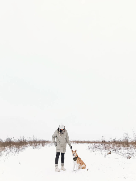Κομψό hipster κορίτσι περπάτημα με χαριτωμένο χρυσός σκύλος κρύο χιονισμένο  - Φωτογραφία, εικόνα