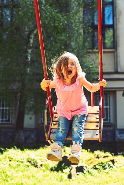 Great pleasure. romantic little girl on the swing, sweet dreams. Happy laughing child girl on swing. Small kid playing in summer. childhood daydream .teen freedom. Playground in park - Photo, image