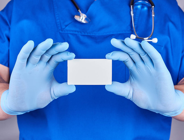 青のラテックス手袋を身に着けている男性医師は、空白を保持しています。  - 写真・画像