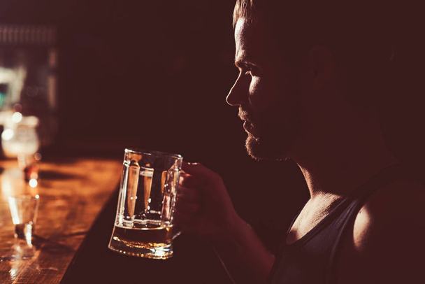A cold beer after work. Handsome man drink beer at bar counter. Man drinker in pub. Alcohol addict with beer mug. Beer restaurant. Alcohol addiction and bad habit. Addicting to alcoholic drink - Photo, Image