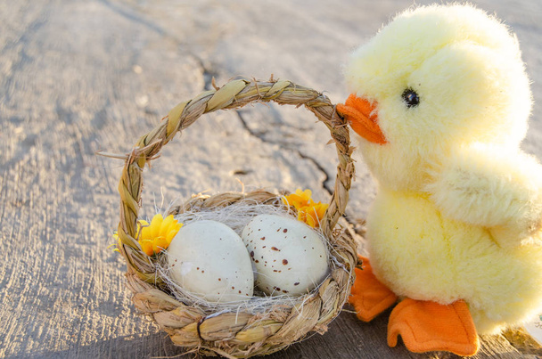 cute little chicken toy and basket with two easter eggs on the stone path - easter concept - Photo, Image