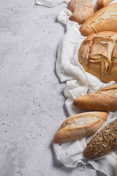Fresh bread on a gray concrete background. Top view with copy space - Zdjęcie, obraz