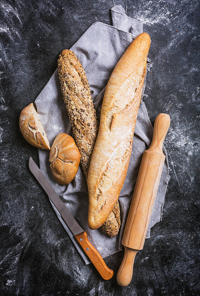Fresh bread and knife on a black background. Top view with copy space - Foto, afbeelding