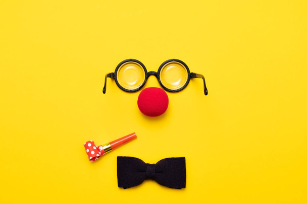 Funny glasses, red clown nose and tie lie on a colored background, like a face. - Fotoğraf, Görsel