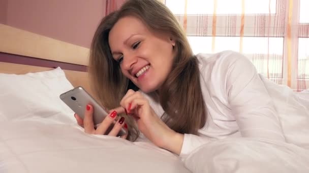 Young smiling woman chatting online with smartphone - 映像、動画