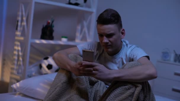 Nervous teenage boy typing on phone, bullying, suicidal internet communities - Кадры, видео