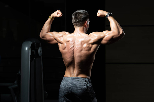 Muscular Man Flexing Muscles Rear Double Biceps Pose - Foto, afbeelding