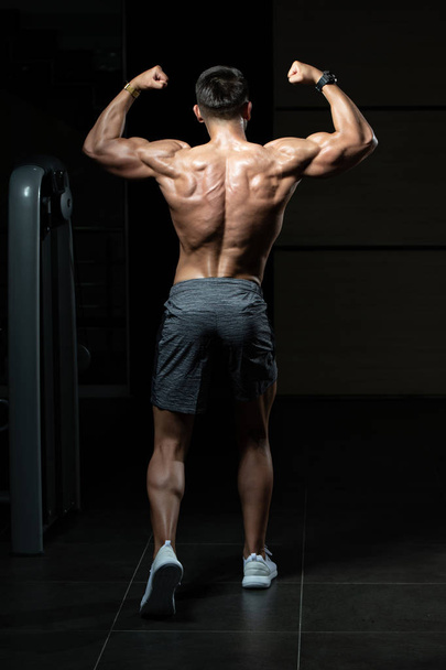 Muscular Man Flexing Muscles Rear Double Biceps Pose - Valokuva, kuva