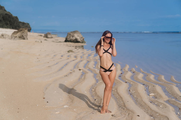sexy Mädchen im Badeanzug mit Sonnenbrille posiert am Sandstrand - Foto, Bild