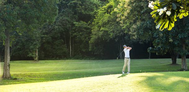 Молодой азиат играет в гольф на красивом естественном поле для гольфа
 - Фото, изображение