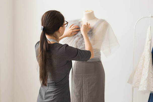 Dressmaker, tecnologías, diseñador de moda y concepto de sastrería: joven diseñadora de moda que trabaja en su sala de exposición
 - Foto, Imagen