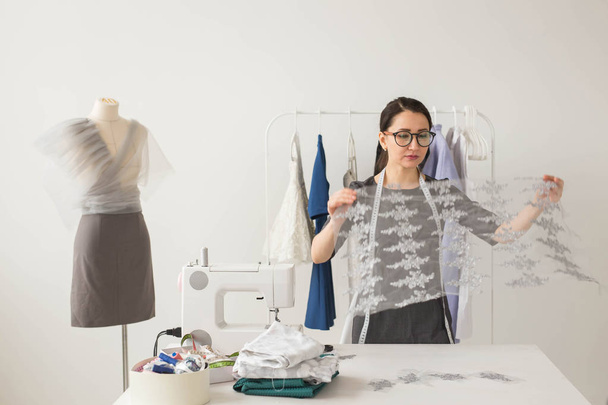 Naaister, technologieën, mode-ontwerper en kleermaker concept - jonge vrouwelijke mode-ontwerper werkt in haar showroom - Foto, afbeelding