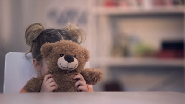 Sad female kid covering face by teddy bear toy, family problem, loneliness abuse - Footage, Video