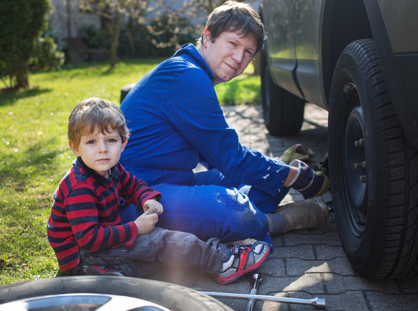 küçük bir çocuk ve babası tekerlekli araba değiştirme - Fotoğraf, Görsel