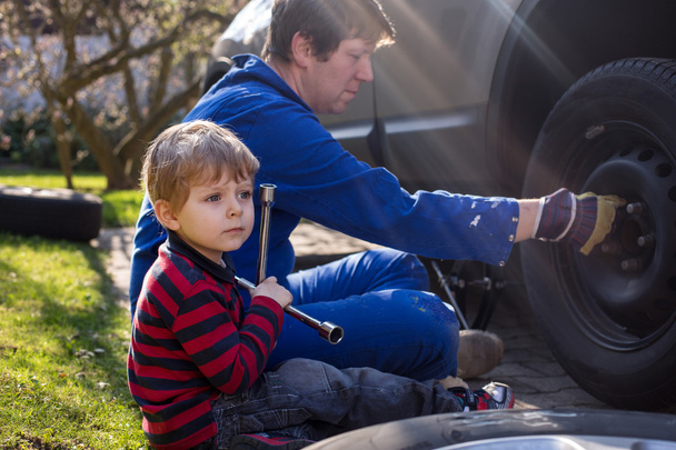 kleine jongen en zijn vader veranderende wiel op auto - Foto, afbeelding