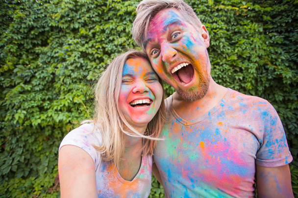 Festival of holi and technology concept - young couple making selfie at the festival - Foto, afbeelding