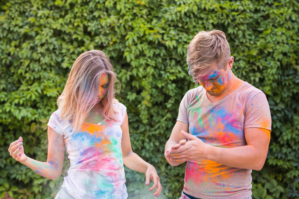 Vacances, holi et concept de personnes - Couple heureux s'amuser avec de la poudre multicolore sur leurs visages
 - Photo, image