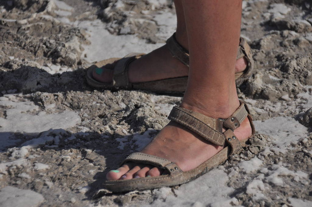 Ze lopen in sandalen op de bodem van een gedroogde en gebarsten lake Akrotiri in Cyprus. - Foto, afbeelding
