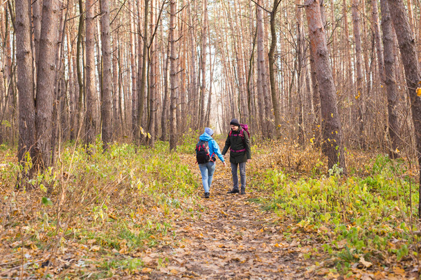 Travel, tourism, hike and people concept - Couple with backpacks walking in the autumn forest, back view - Photo, Image
