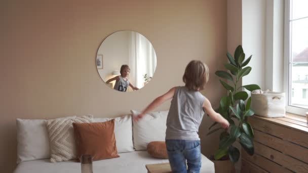 Confident kid looking at his muscles in mirror imagining that he is super hero - Záběry, video