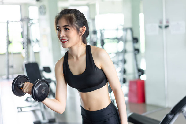 ダンベル トレーニング運動筋肉の建物の強い重量フィットネス ジムや健康的なライフ スタイルの彼女の上腕筋の基本的な訓練を持つ女性 - 写真・画像